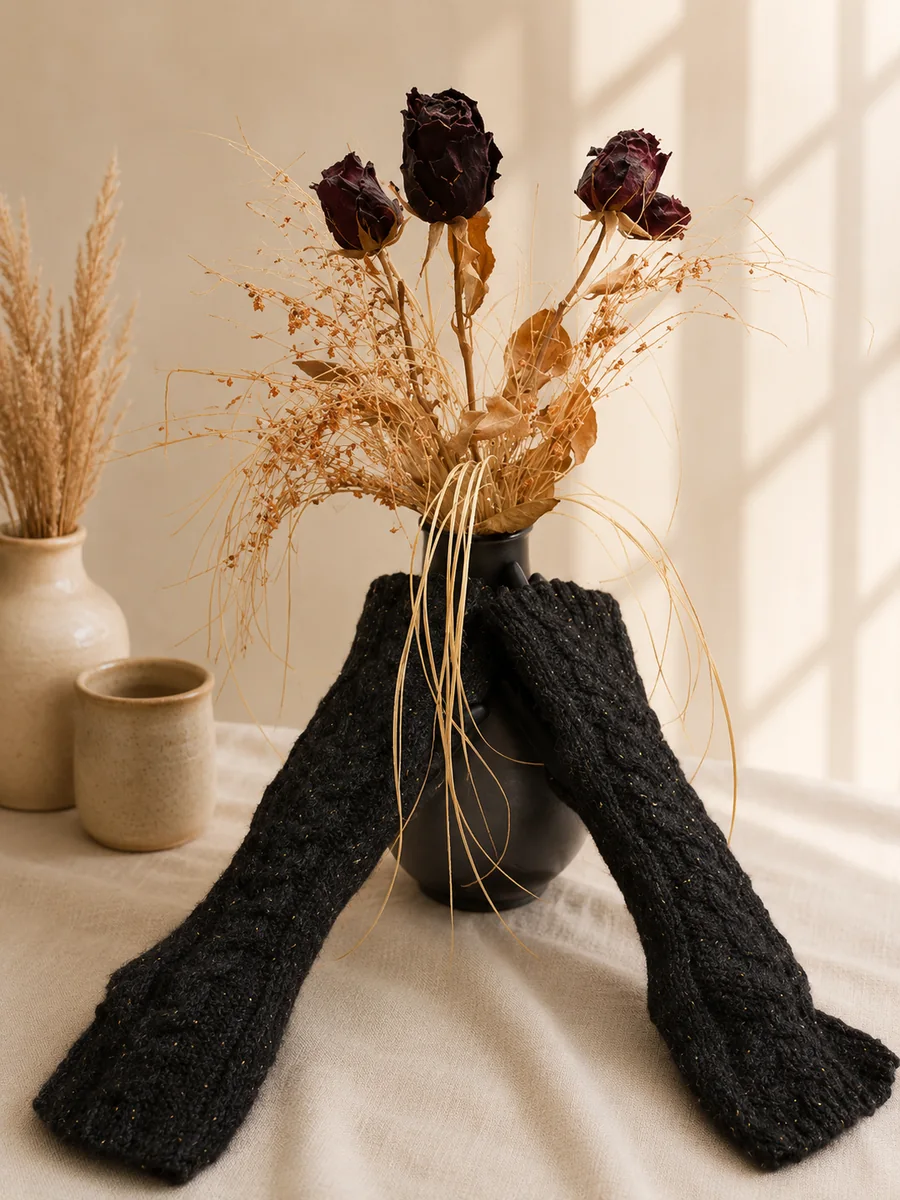 Handgestrickte Stulpen in Anthrazit vor einem warmen, neutralen Hintergrund.