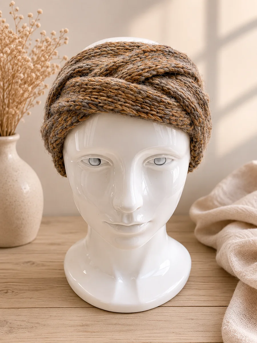 Frontal aufgenommenes handgestricktes Stirnband in warmen Braun- und Beigetönen.