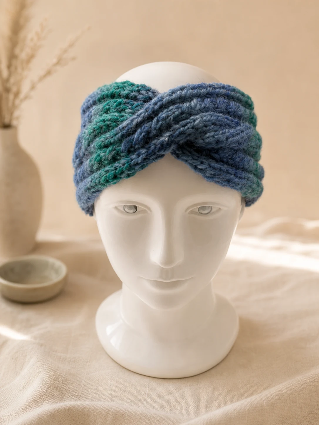 Handgestricktes Stirnband in Blau und Grün, Produktfoto.