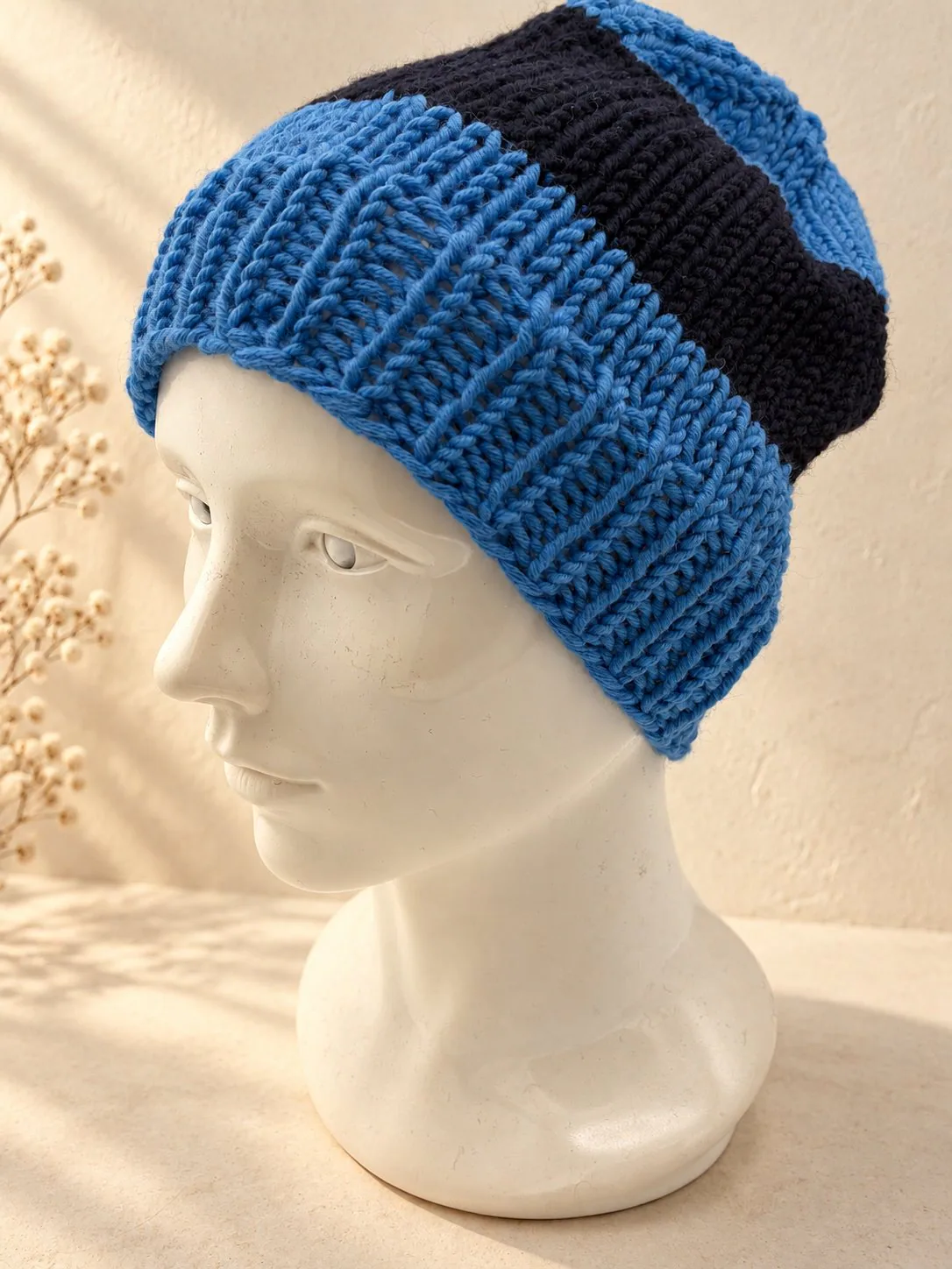 Handgestrickte Mütze in Blau und Schwarz, Produktfoto.