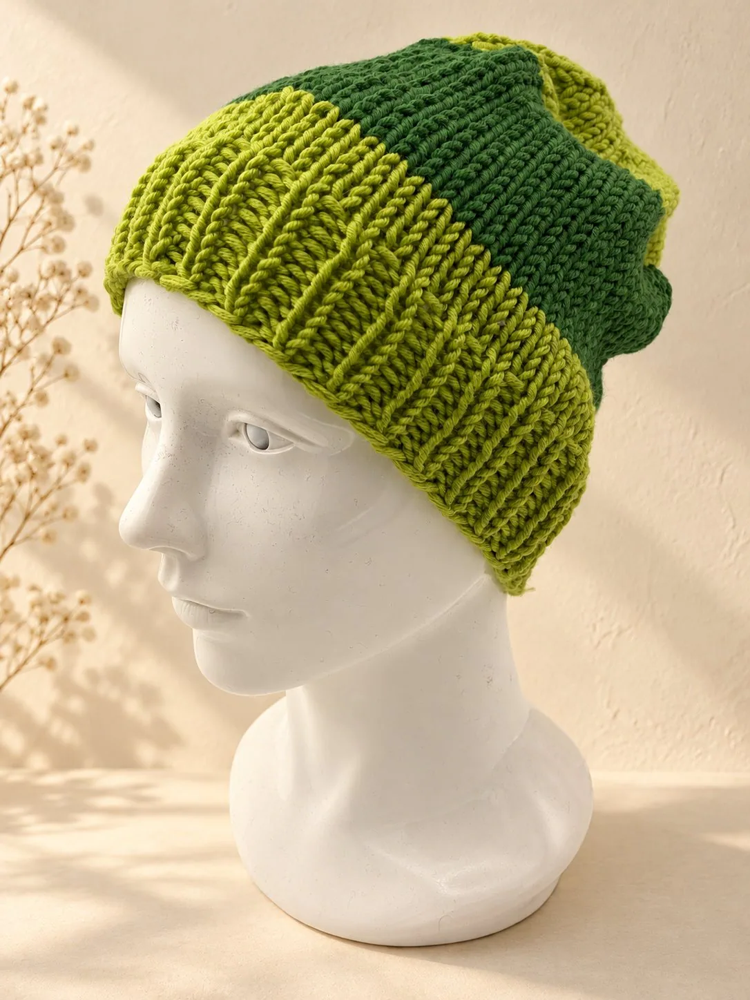 Handgestrickte Mütze in Grün und Schwarz, Produktfoto.