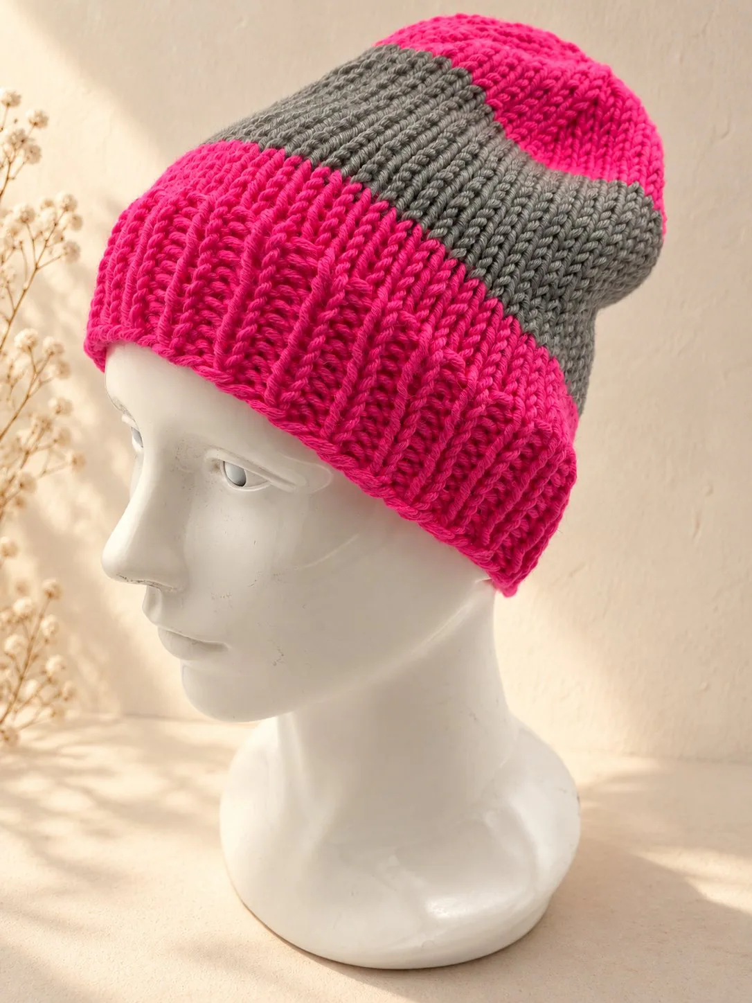 Handgestrickte Mütze in Pink und Grau, Produktfoto.