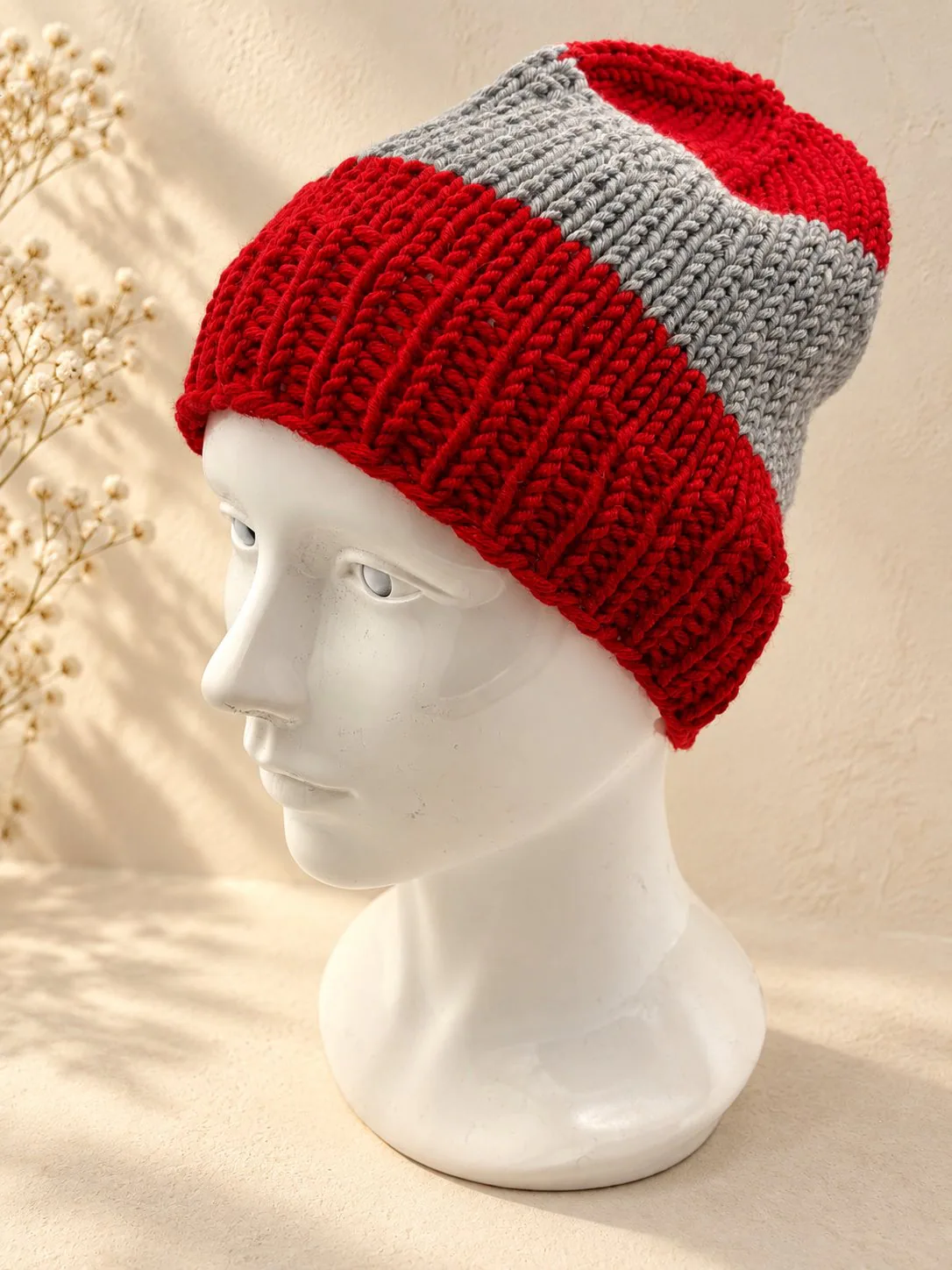 Handgestrickte Mütze in Rot und Grau, Produktfoto.