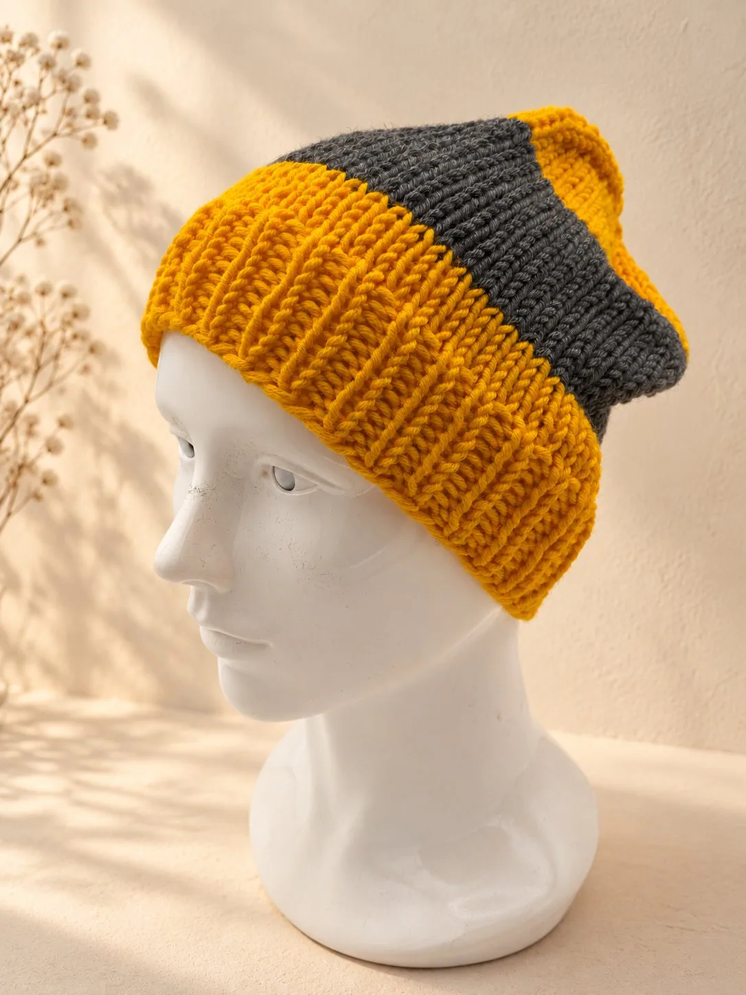 Handgestrickte Mütze in Senfgelb und Grau, Produktfoto.