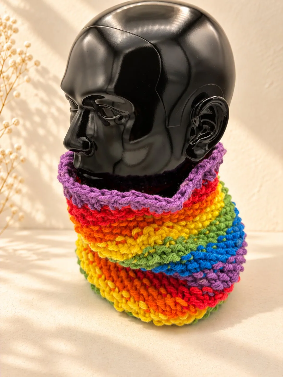 Handgestrickter Schlauchschal in Regenbogenfarben mit gelbem Akzent, Produktfoto.